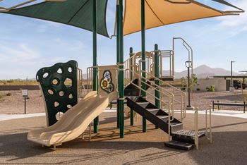 A playground with a yellow slide and a green umbrella.
